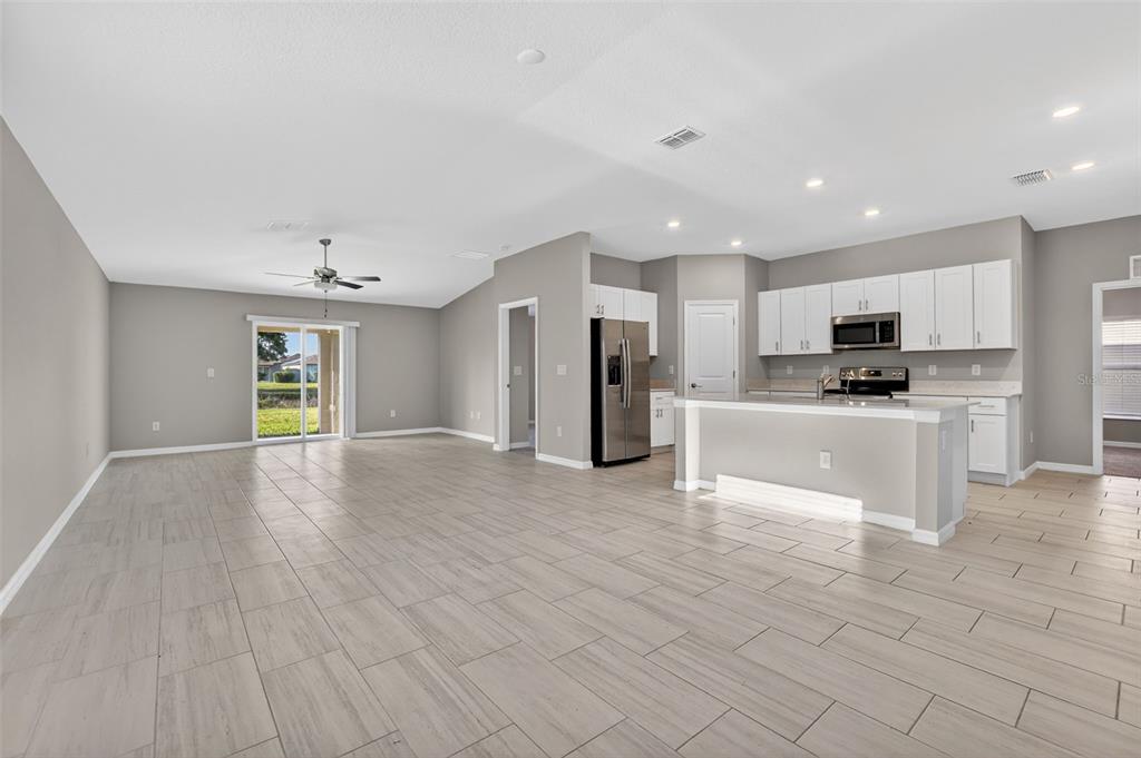 An open-concept living area features light-colored tile flooring, a kitchen island, and white cabinetry — 13187 PALMERSTON ROAD, RIVERVIEW, FL