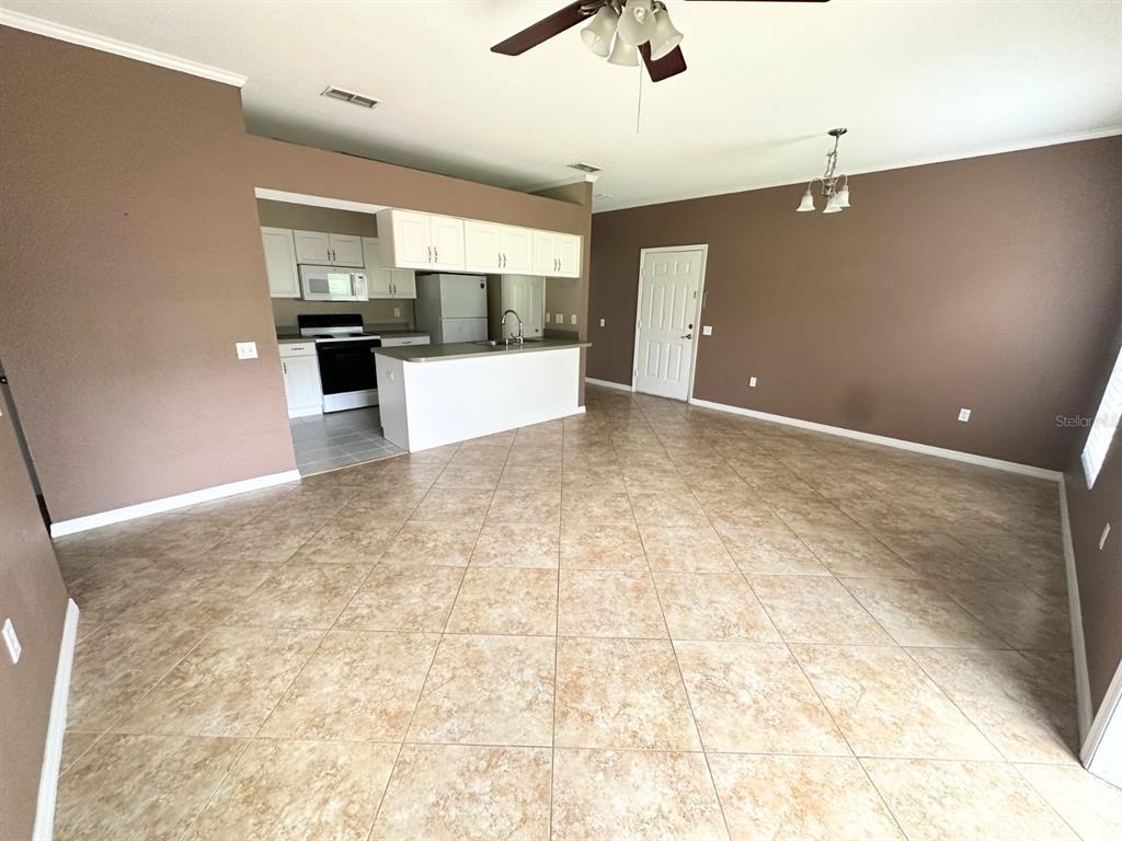 An open-concept kitchen with white cabinets and a breakfast bar overlooks a tiled living area — 1003 EAGLE POND DRIVE UNIT 1003, WINTER HAVEN, FL