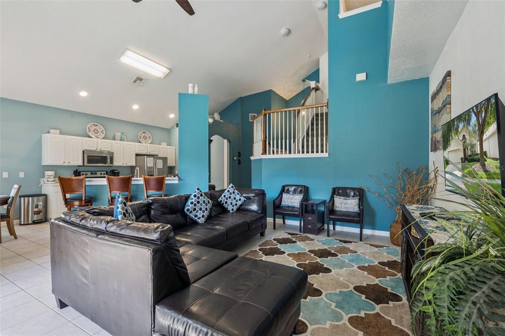 A living room with a black sectional sofa, blue walls, and a staircase — 2648 DAULBY STREET, KISSIMMEE, FL