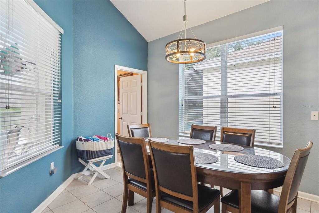A dining area features a glass-topped table, six chairs, a chandelier, and blue walls — 2648 DAULBY STREET, KISSIMMEE, FL