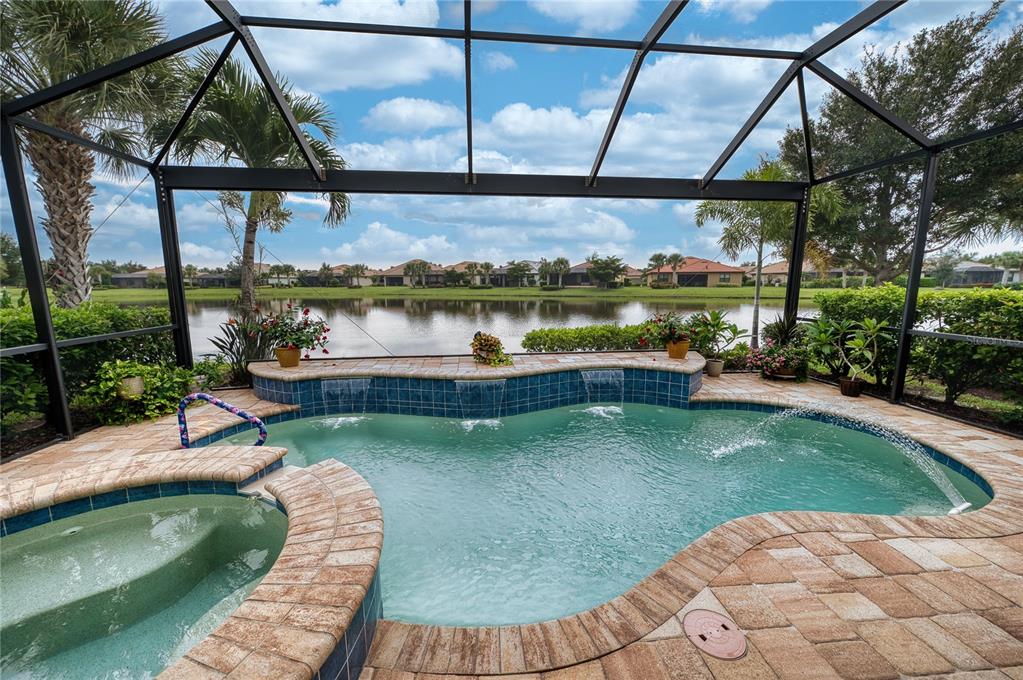 A screened-in pool and spa area with a water feature overlooking a lake — 17044 KENTON TERRACE, BRADENTON, FL