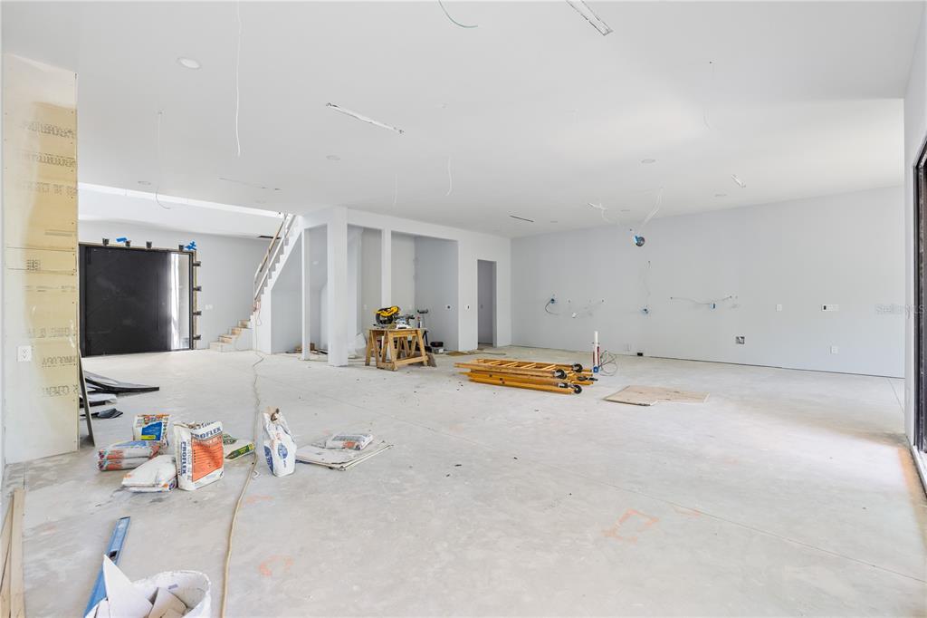 A modern entryway features light wood floors, a black front door, and a glass-enclosed wine cellar — 4709 W ESTRELLA STREET, TAMPA, FL