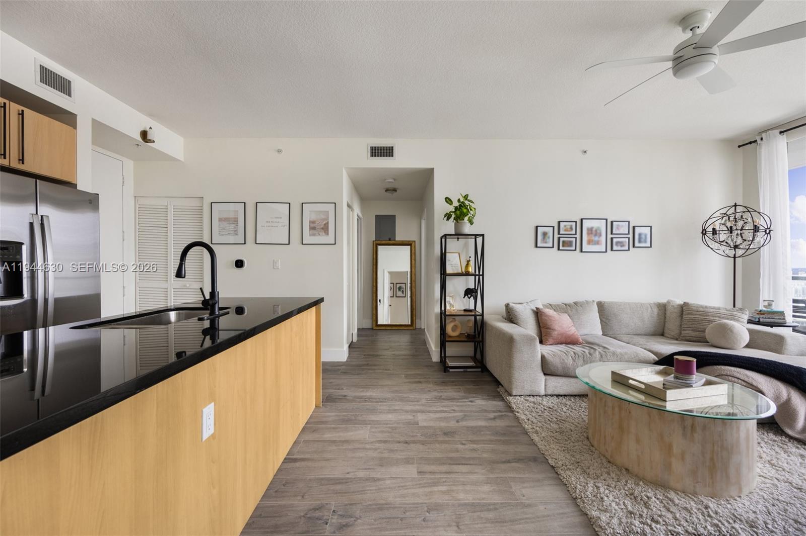 A modern open-concept kitchen and living area features light wood cabinetry and gray flooring — 1111 SW 1st Ave, Miami FL 33130, MIAMI, FL