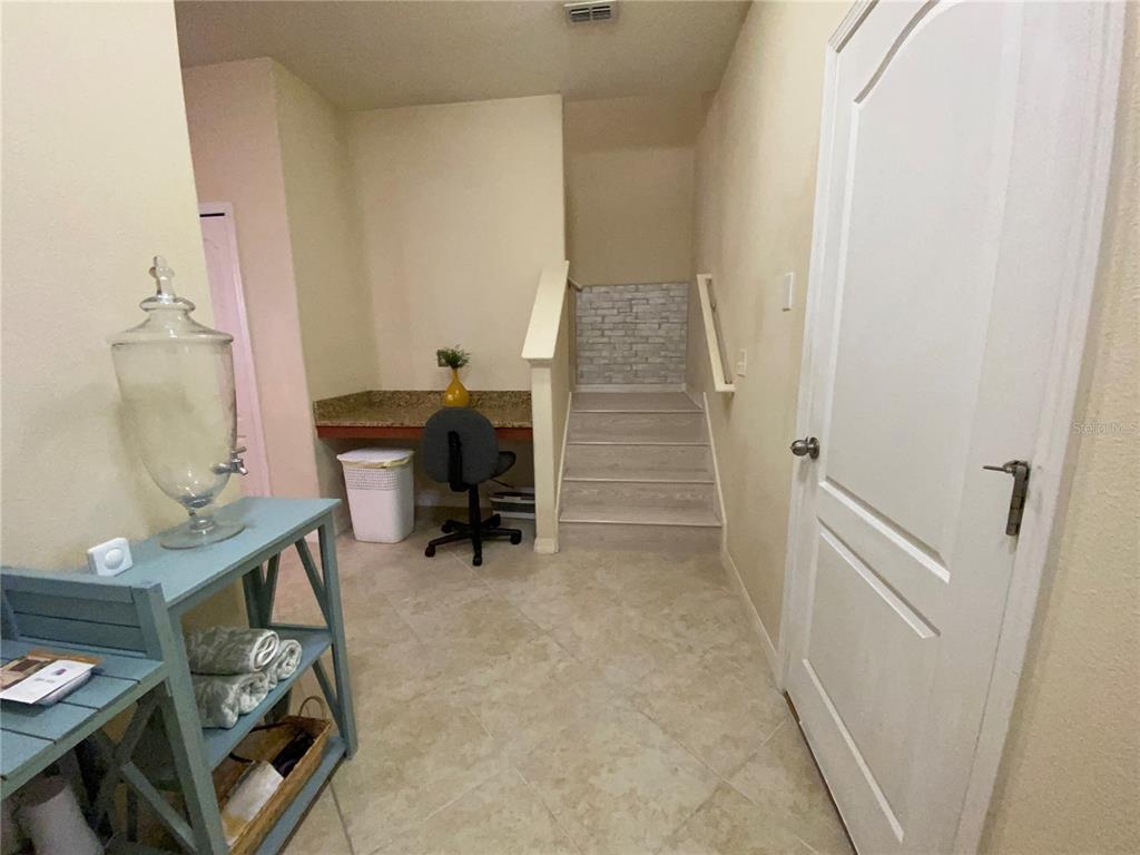 A hallway features a built-in desk, a staircase with brick-patterned wallpaper, and a blue console table — 13733 ROSETTE ROAD, HUDSON, FL