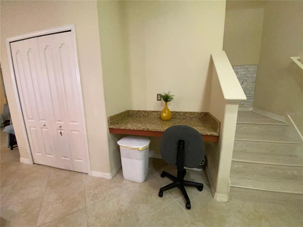 A built-in granite desk sits in a nook next to a closet and staircase — 13733 ROSETTE ROAD, HUDSON, FL