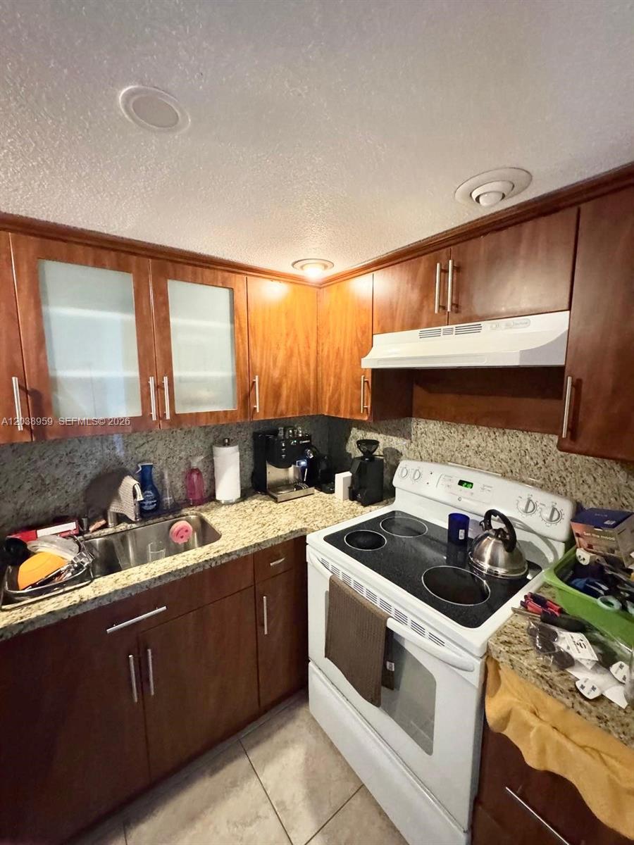 A kitchen features dark wood cabinets, granite countertops, and white appliances — 1100 Alton Rd # 5D, Miami Beach FL 33139, MIAMI BEACH, FL