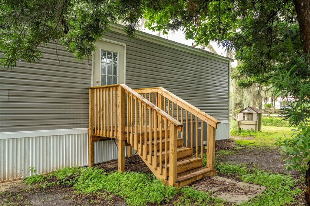 A wooden staircase with railings leads to a door on the side of a mobile home — 36720 EMERALDA ISLAND ROAD, LEESBURG, FL