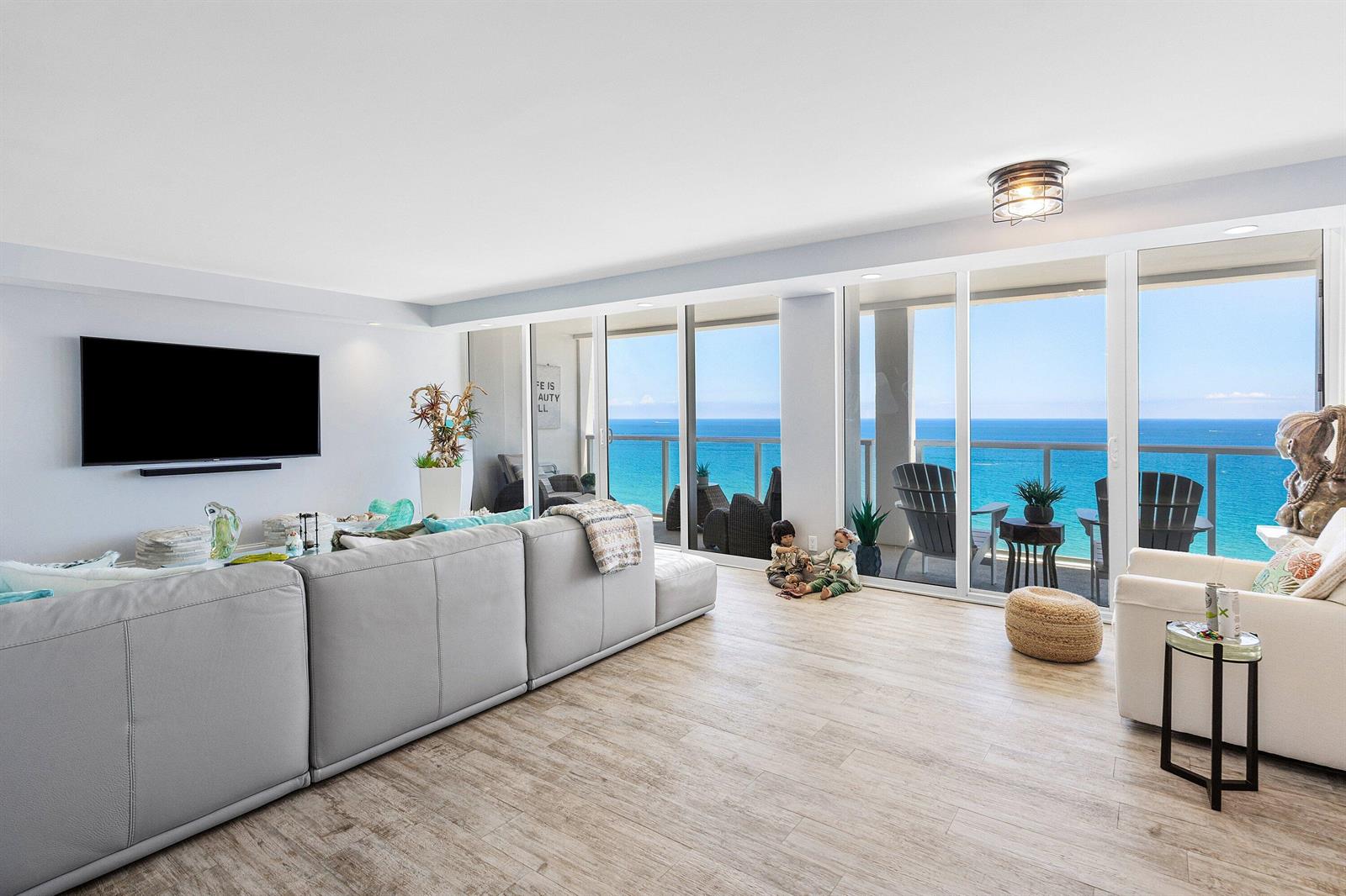 A living room with a large sectional sofa, light wood floors, and floor-to-ceiling ocean views — 2800 S Ocean Boulevard # 17l, Boca Raton FL 33432, BOCA RATON, FL