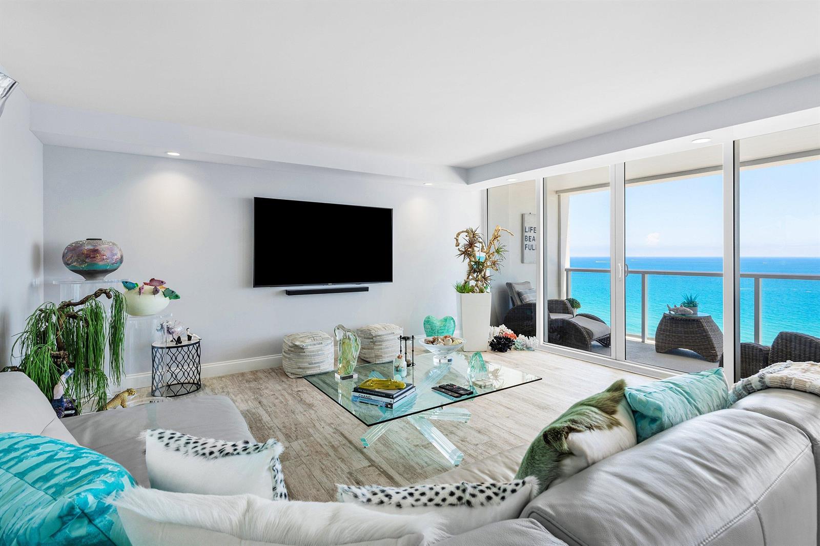 A living room features a glass coffee table, a wall-mounted television, and a balcony view — 2800 S Ocean Boulevard # 17l, Boca Raton FL 33432, BOCA RATON, FL