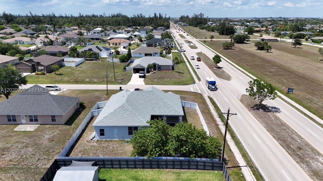An aerial view shows a residential neighborhood with a light blue house and a road — 1602 SW 14th St, Cape Coral FL 33991, CAPE CORAL, FL