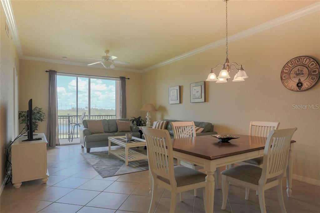 A dining area and living room with tile floors, a ceiling fan, and a balcony view — 8309 GRAND ESTUARY TRAIL UNIT 204, BRADENTON, FL