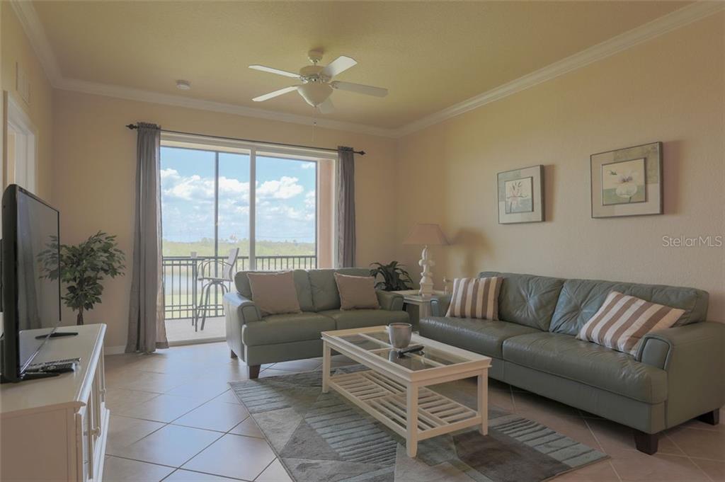 A living room with two leather sofas, a coffee table, and a sliding glass door — 8309 GRAND ESTUARY TRAIL UNIT 204, BRADENTON, FL