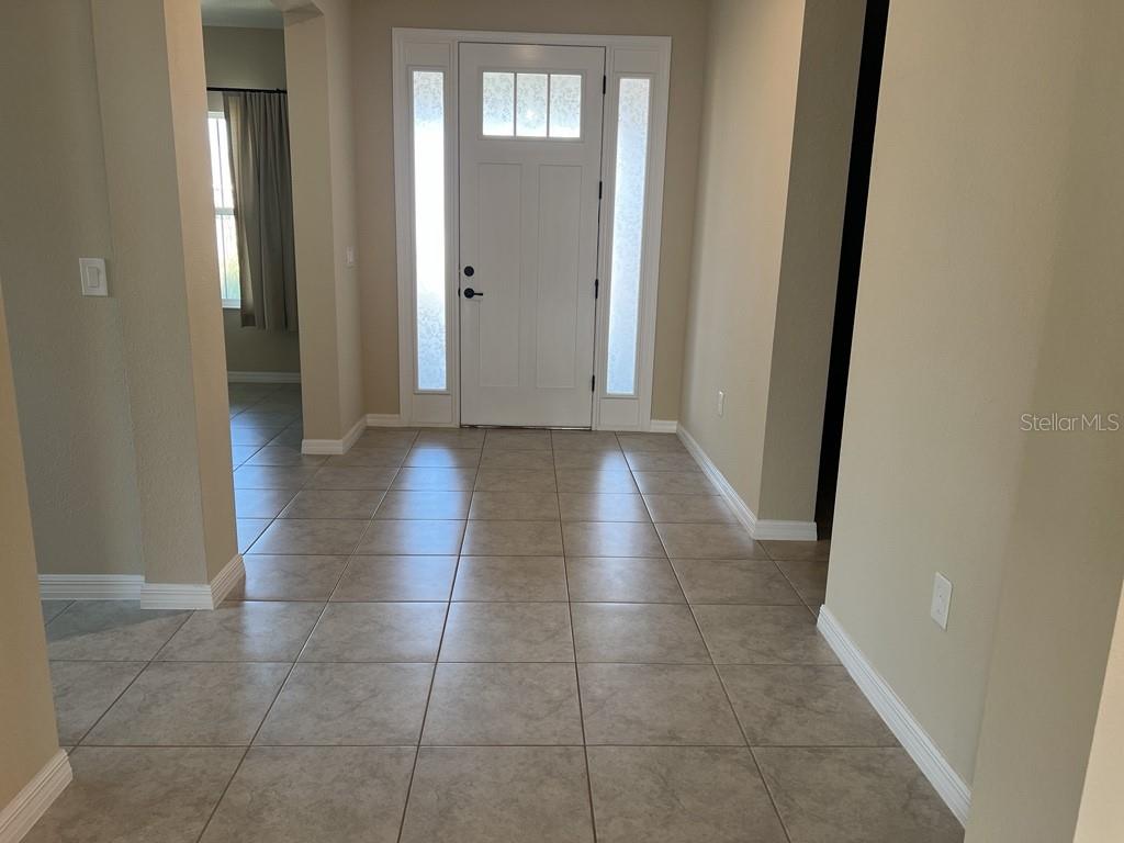A tiled entryway features a white front door with sidelights and a nearby hallway — 10376 SW 99 STREET, OCALA, FL
