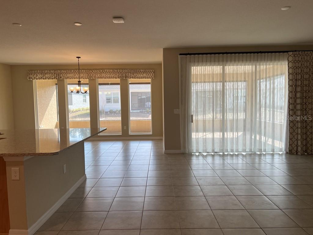 A bright room with tile flooring, a kitchen island, large windows, and sliding glass doors — 10376 SW 99 STREET, OCALA, FL