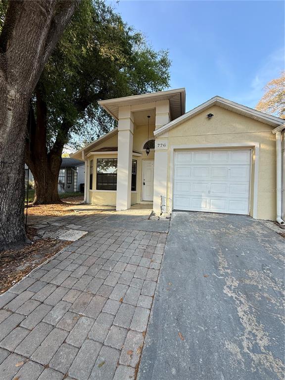 A single-story house with a paved driveway, a one-car garage, and a large tree — 776 WOLF CREEK COURT, APOPKA, FL