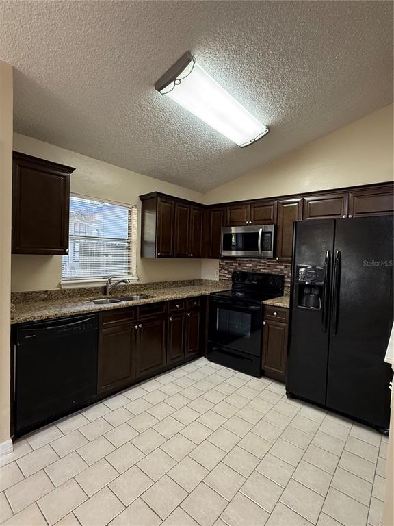 A kitchen features dark wood cabinets, granite countertops, black appliances, and light-colored tile flooring — 776 WOLF CREEK COURT, APOPKA, FL