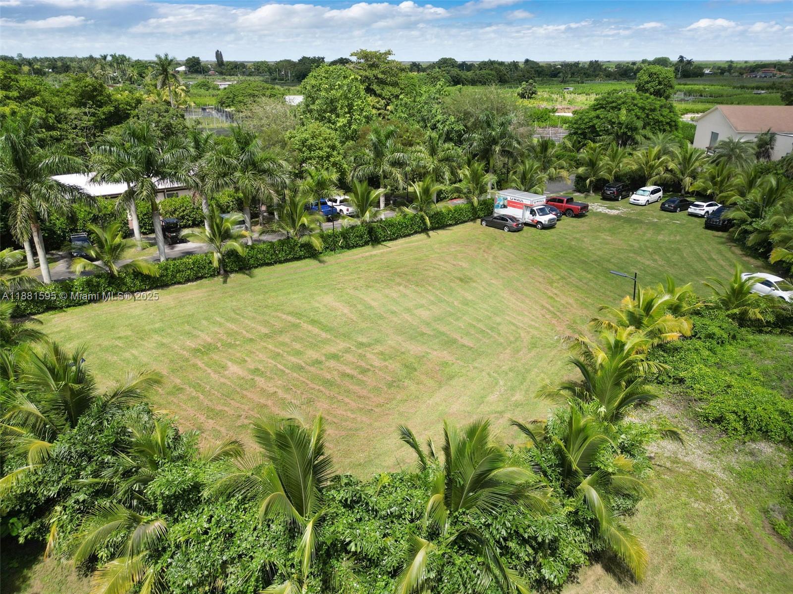 An aerial view of a large, rectangular grassy lot surrounded by palm trees and vehicles — 20701 SW 216th St, Miami FL 33170, MIAMI, FL