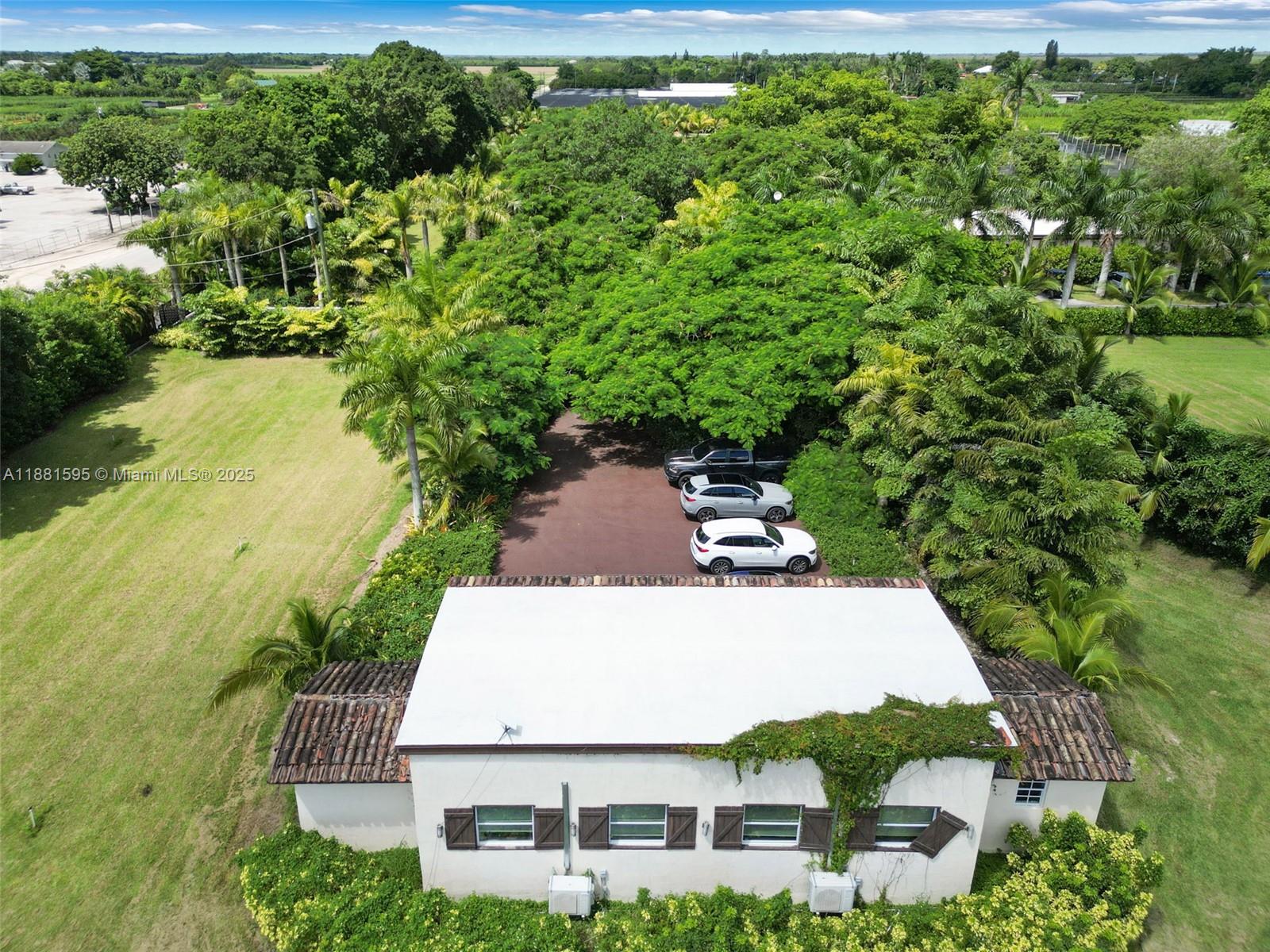 An aerial view shows a house with a white roof, parking area, and surrounding trees — 20701 SW 216th St, Miami FL 33170, MIAMI, FL