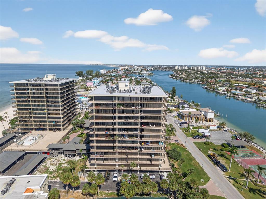 An aerial view shows two high-rise apartment buildings situated between a beach and a waterway — 7600 BAYSHORE DRIVE UNIT 902, TREASURE ISLAND, FL