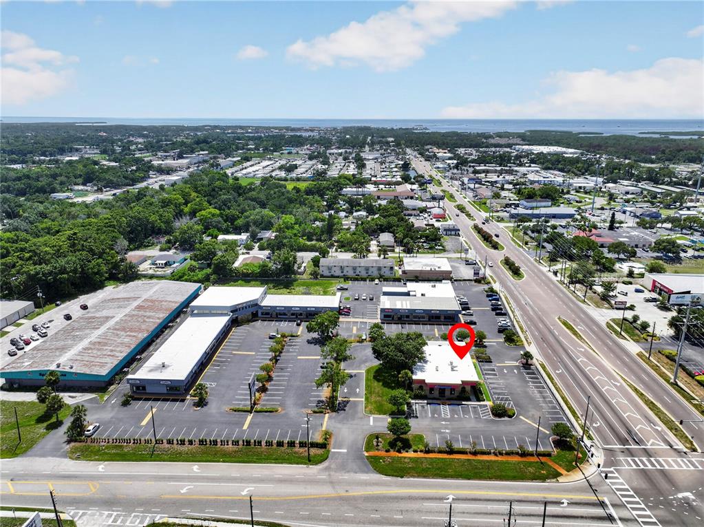 This aerial view shows a commercial plaza with multiple buildings and parking lots — 6486 E RIDGE ROAD E, PORT RICHEY, FL