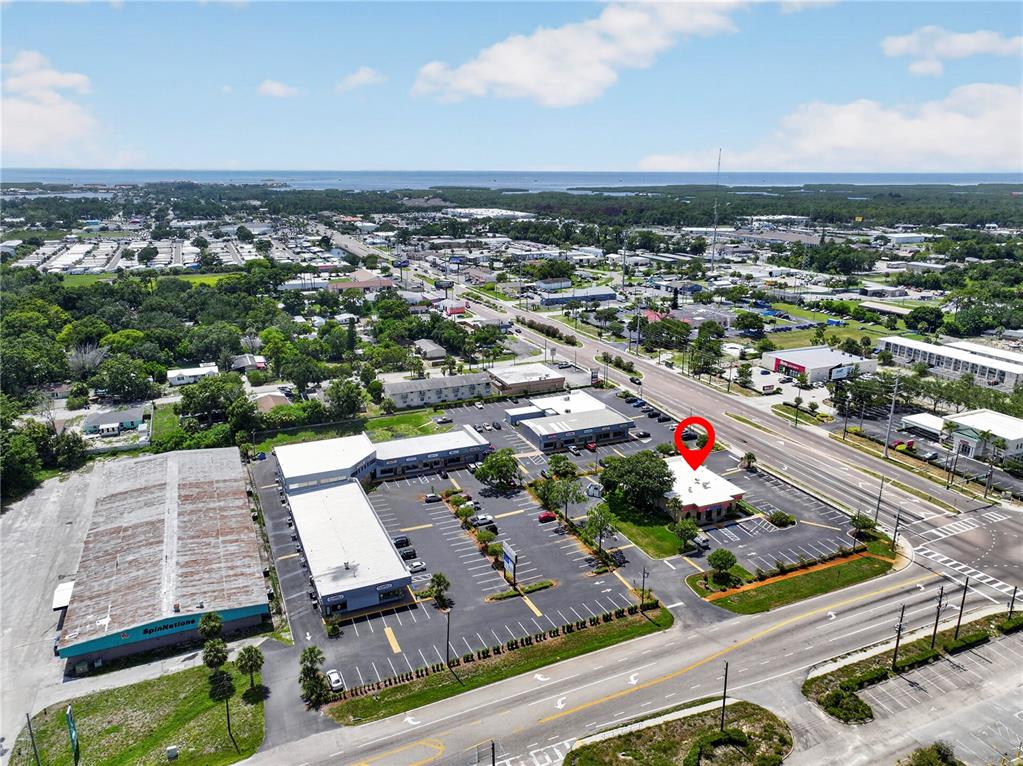 An aerial view shows a commercial plaza with multiple buildings, parking lots, and a red pin — 6486 E RIDGE ROAD E, PORT RICHEY, FL