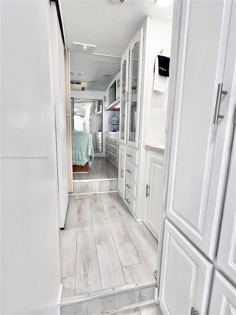 A narrow hallway with light wood-look flooring leads to a bedroom in a recreational vehicle — 325 Calusa St #5, Key Largo FL 33037, KEY LARGO, FL