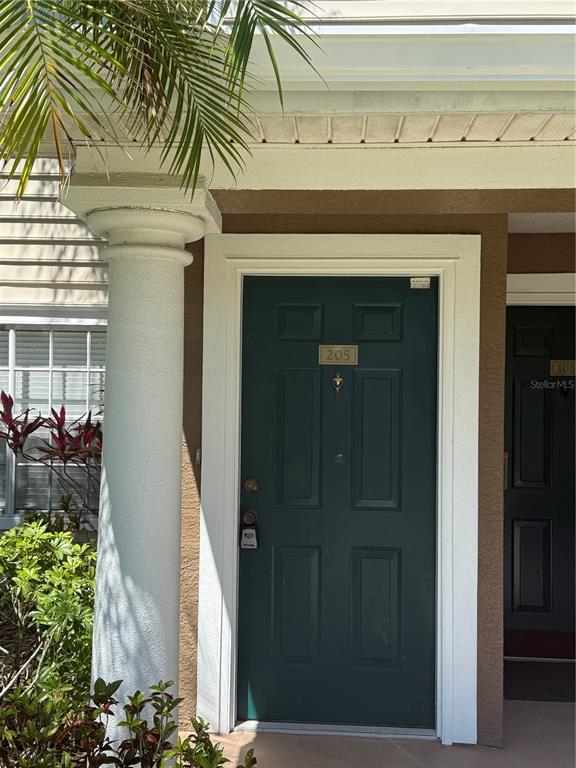 A dark green front door with the number 205 is framed by a white column — 8932 MANOR LOOP UNIT 205, LAKEWOOD RANCH, FL