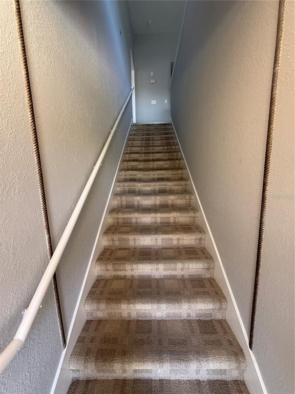 A carpeted staircase with a white handrail leads upward between two gray walls — 8932 MANOR LOOP UNIT 205, LAKEWOOD RANCH, FL
