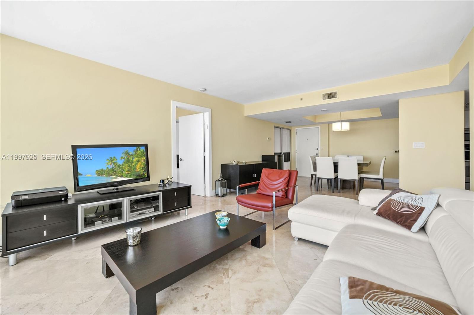 A living room features a white sectional sofa, a red armchair, and a dark coffee table — 650 West Ave # 1104, Miami Beach FL 33139, MIAMI BEACH, FL