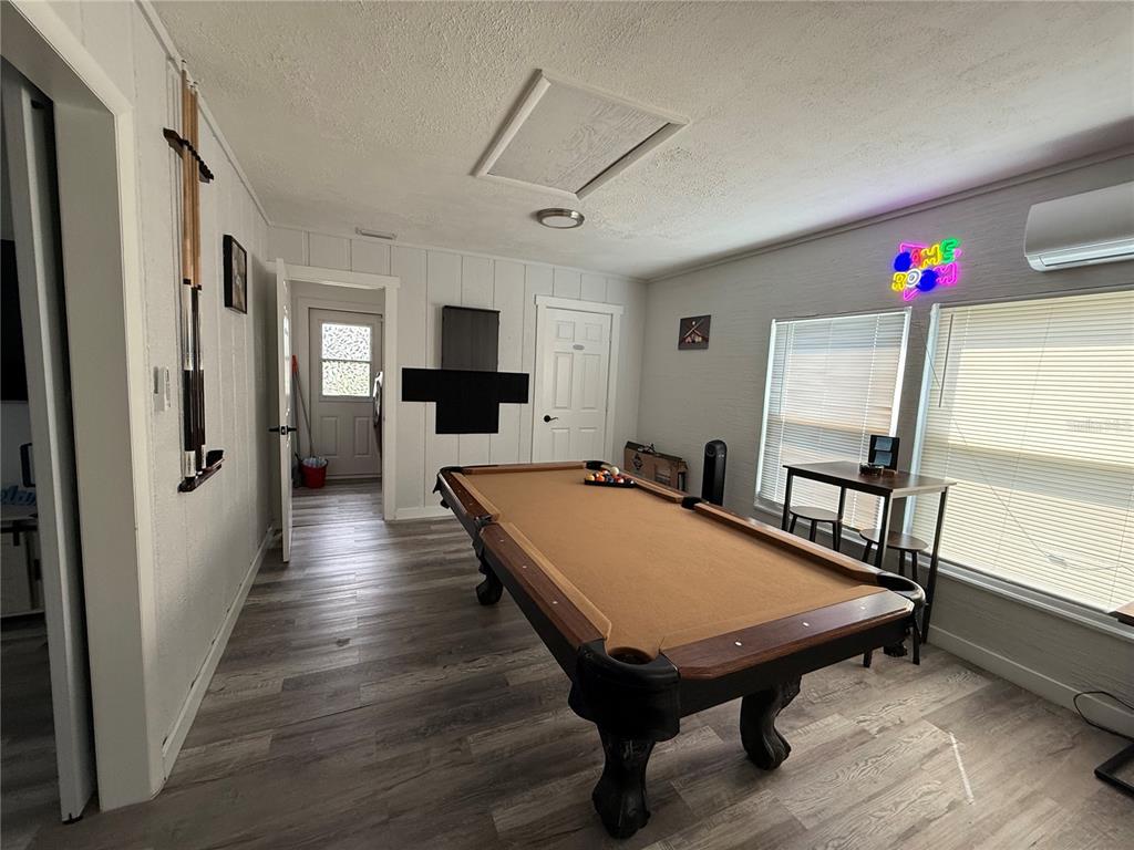 A game room features a pool table, wood-look flooring, and a neon wall sign — 3988 SAN LUIS DRIVE, SARASOTA, FL