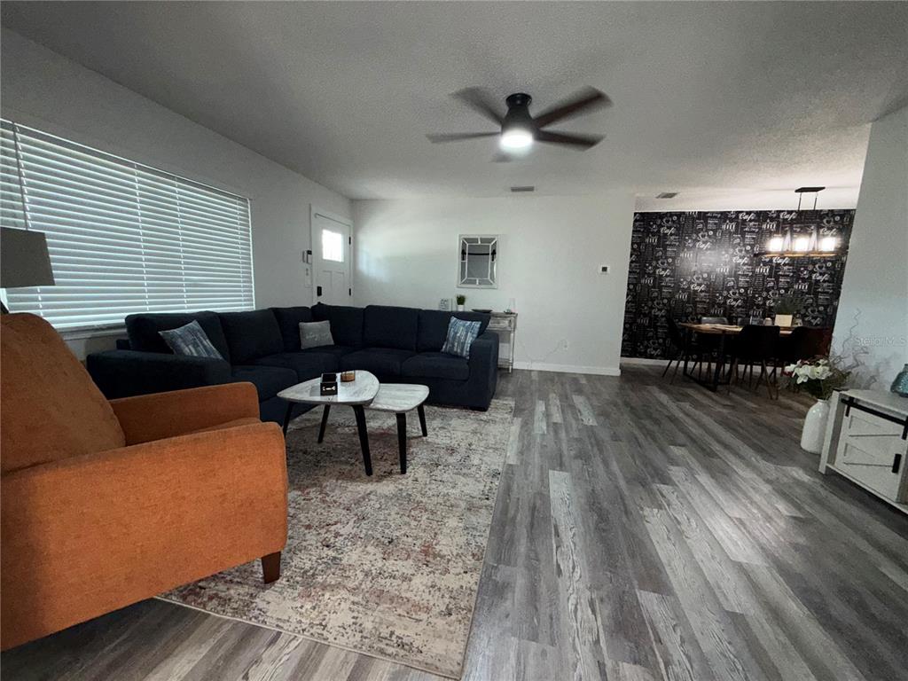 A living room features a dark sectional sofa, an orange armchair, and a dining area — 3988 SAN LUIS DRIVE, SARASOTA, FL