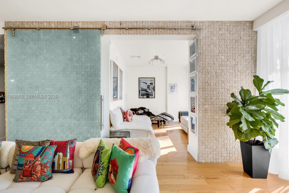 A living room with a sliding glass door leads to a bedroom with wood floors — 10275 Collins Ave # 102, Bal Harbour FL 33154, BAL HARBOUR, FL
