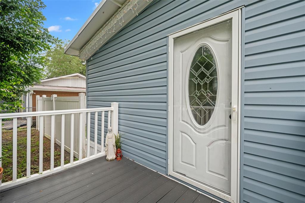 A light blue vinyl-sided house exterior features a white storm door and a wooden deck — 237 MONROE AVENUE, BROOKSVILLE, FL