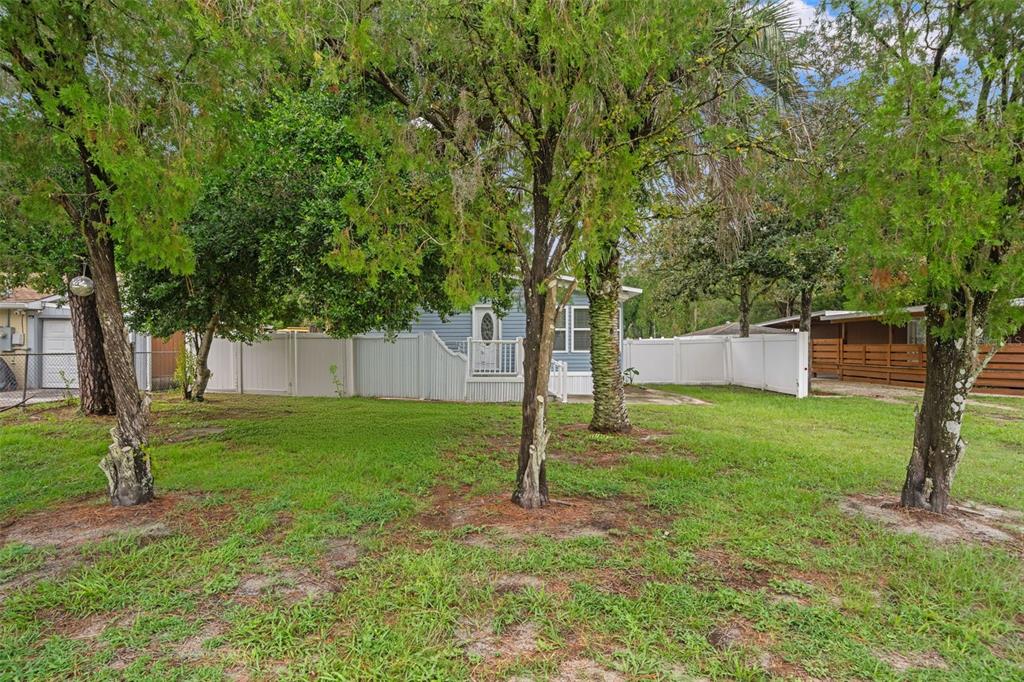 A blue house with a white fence stands behind several trees in a grassy yard — 237 MONROE AVENUE, BROOKSVILLE, FL