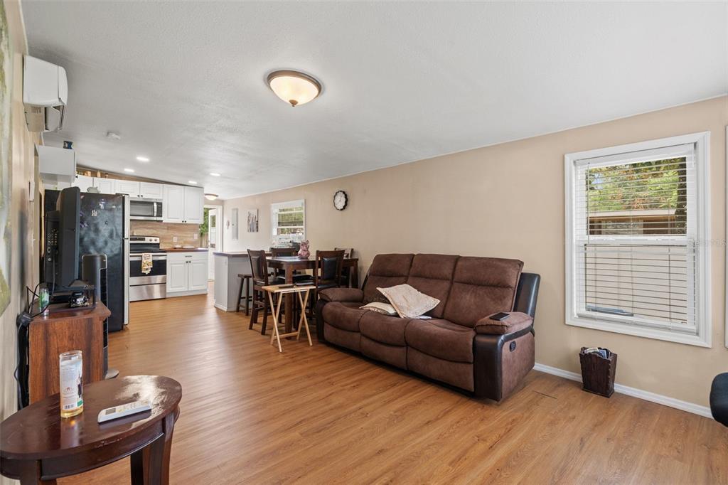 An open-concept living room and kitchen featuring wood-look flooring and a brown reclining sofa — 237 MONROE AVENUE, BROOKSVILLE, FL