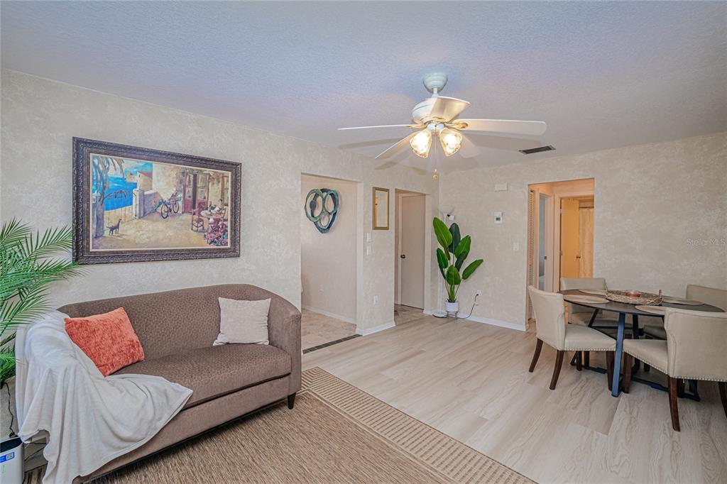 A living and dining area features light wood-look flooring, a ceiling fan, and neutral walls — 24540 HARBORVIEW ROAD UNIT F1, PUNTA GORDA, FL