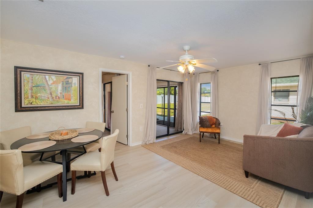 A dining area and living space with light wood floors, a ceiling fan, and patio access — 24540 HARBORVIEW ROAD UNIT F1, PUNTA GORDA, FL