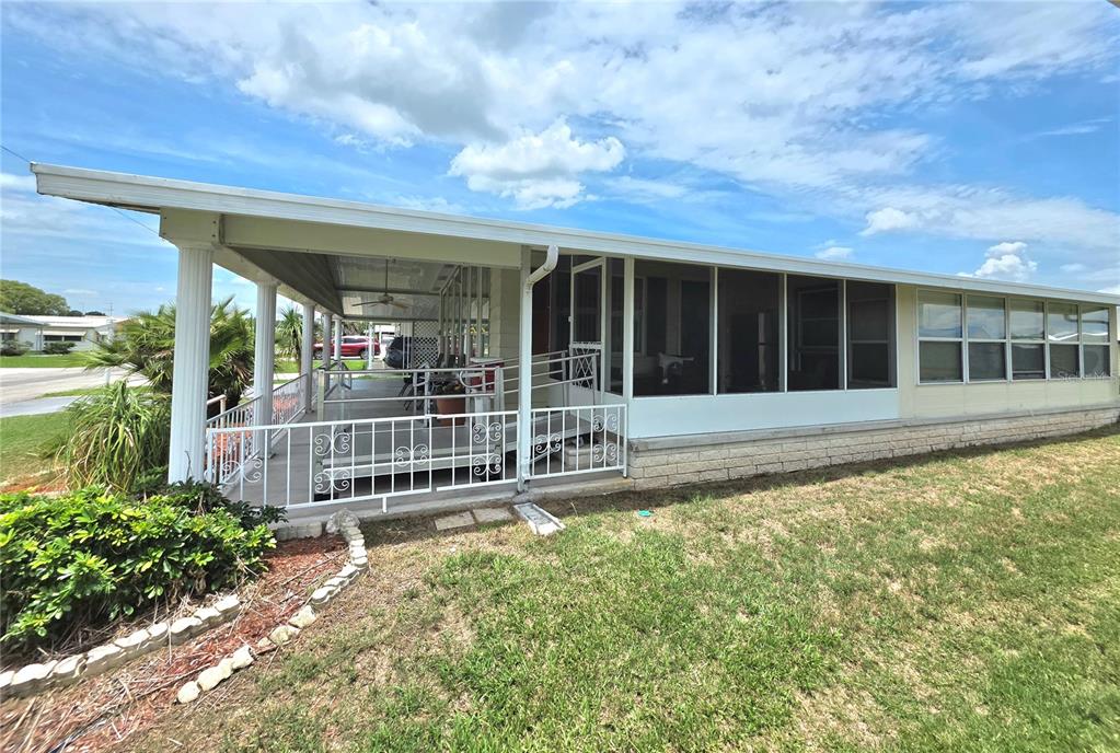 A mobile home features a covered porch with white railings and a screened-in living area — 5334 COMANCHE STREET, ZEPHYRHILLS, FL