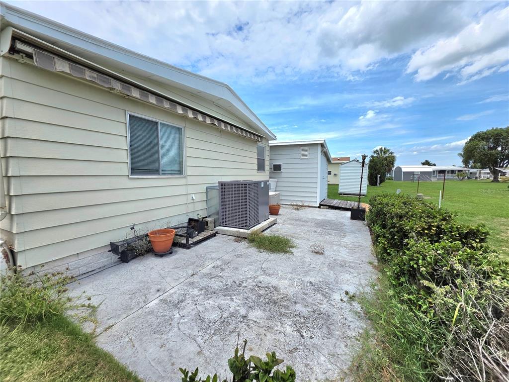 A concrete patio sits beside a light-colored mobile home with an outdoor air conditioning unit — 5334 COMANCHE STREET, ZEPHYRHILLS, FL