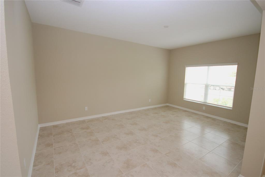 An empty room with beige walls, tile flooring, and a single window — 11415 ACACIA GROVE LANE, RIVERVIEW, FL