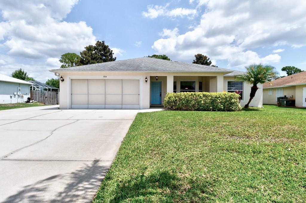 A single-story house with a light-colored exterior, a two-car garage, and a blue front door — SEBASTIAN, FL