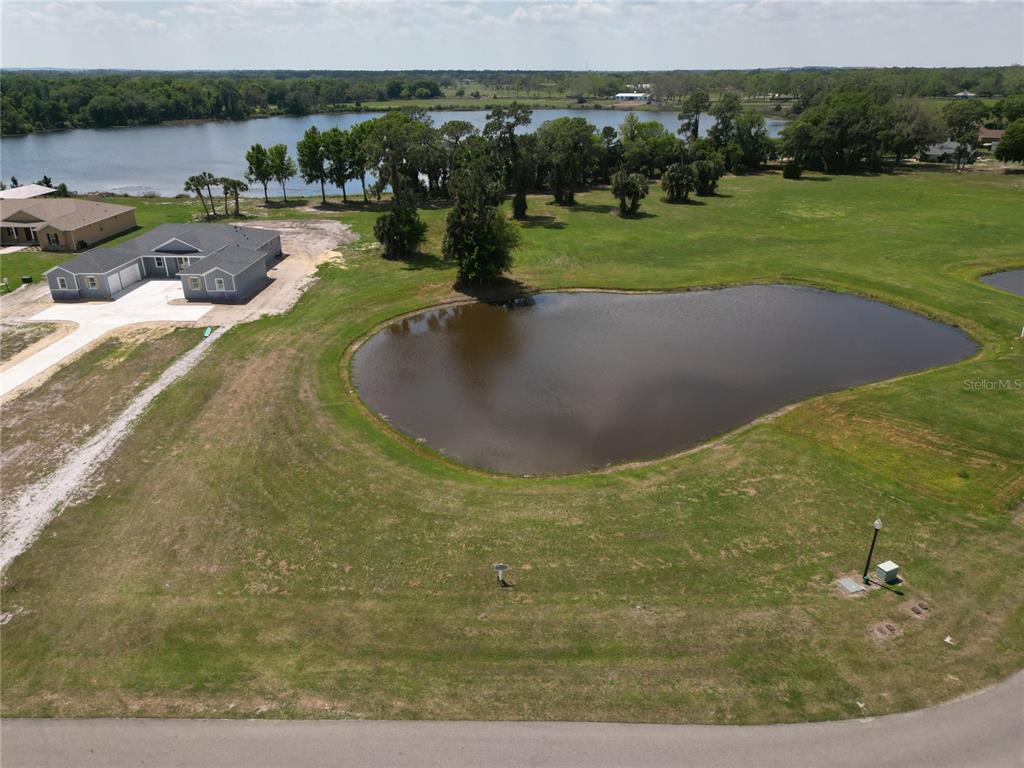 An aerial view shows a pond, a grassy lot, and a house under construction — 3430 LAKE DIANE ROAD, TAVARES, FL