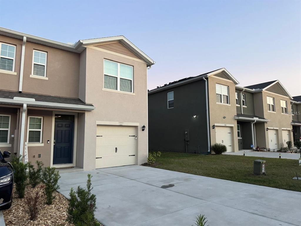A two-story townhouse with a beige stucco facade, a single-car garage, and a concrete driveway — 2730 PUFFIN PLACE, DAVENPORT, FL
