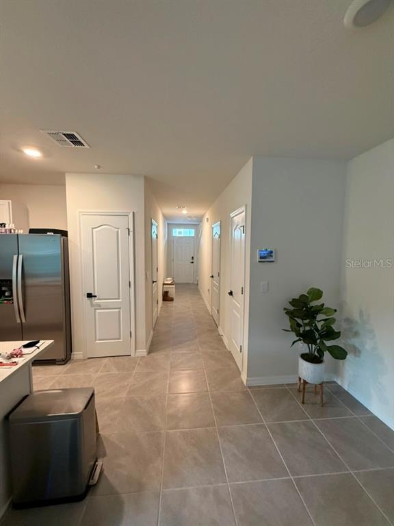A tiled hallway leads past a staircase to a doorway with a view outside — 2730 PUFFIN PLACE, DAVENPORT, FL