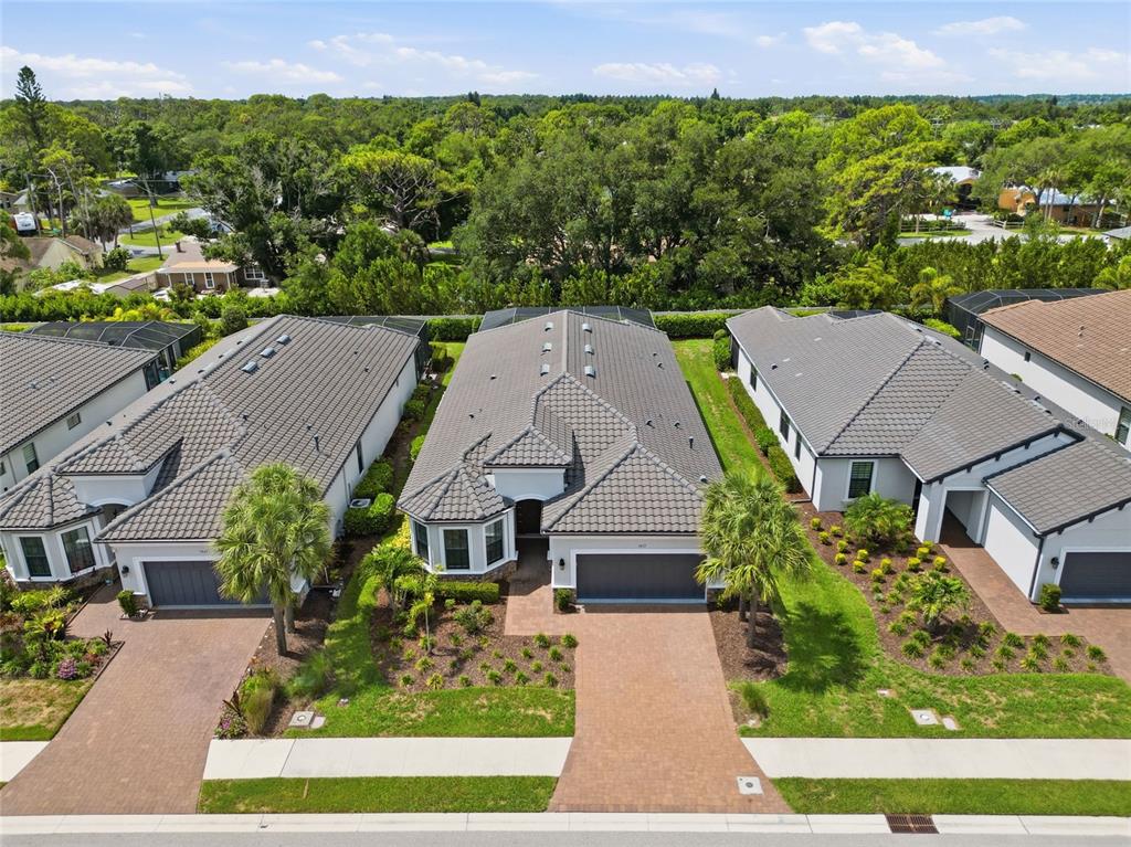 An aerial view shows three suburban houses with tiled roofs and brick driveways — 5617 SCARLOTTI STREET, NOKOMIS, FL