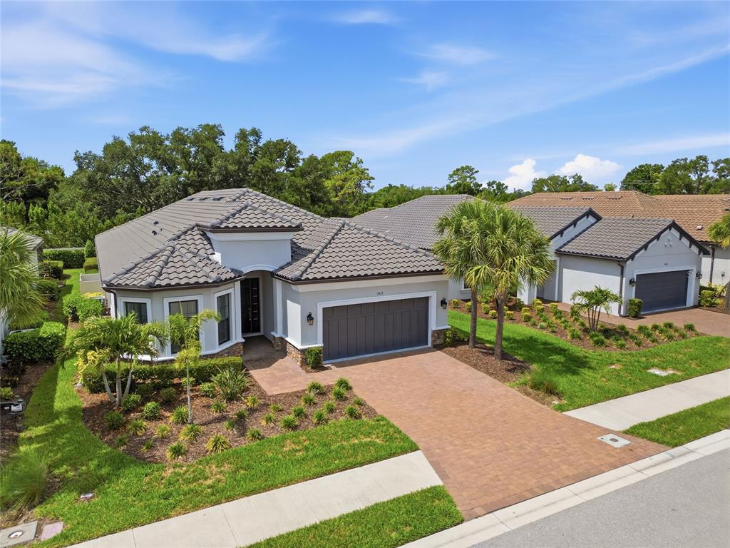 An aerial view of a single-story house with a tiled roof and paver driveway — 5617 SCARLOTTI STREET, NOKOMIS, FL