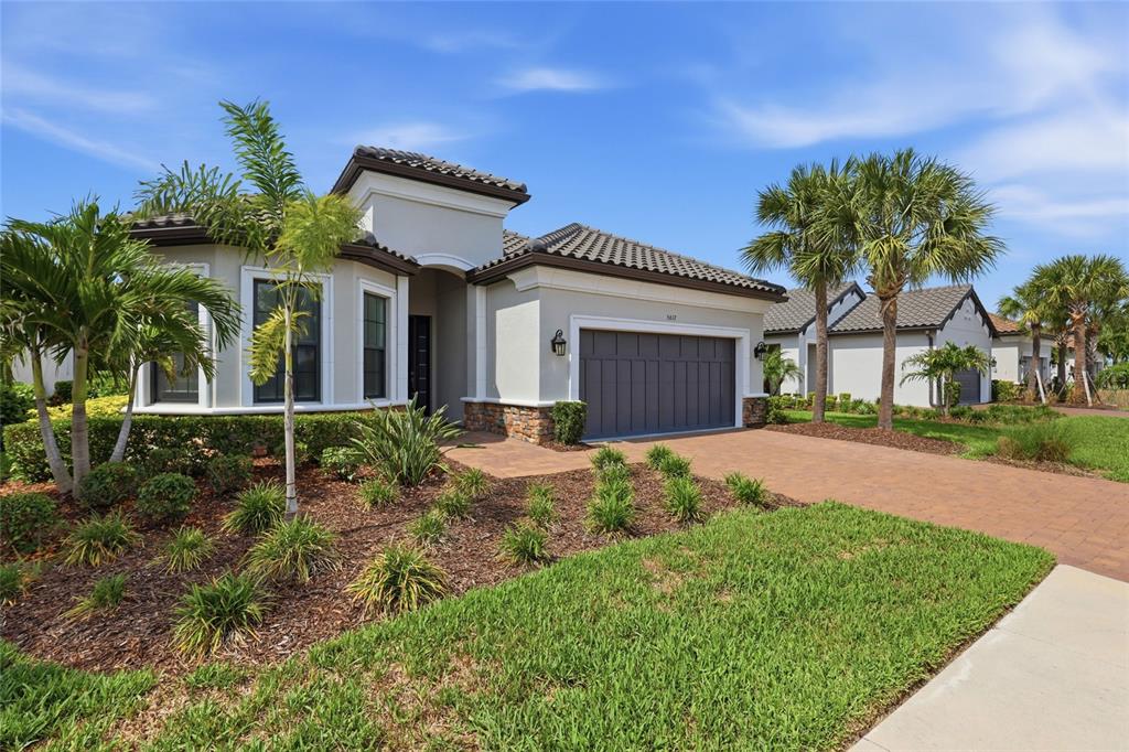 A single-story house with a gray garage, tile roof, and palm trees in the front yard — 5617 SCARLOTTI STREET, NOKOMIS, FL