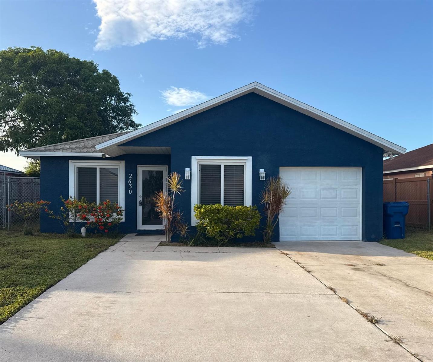 A blue single-story house with a white garage door and a concrete driveway — 2630 W 28th Street, Riviera Beach FL 33404, RIVIERA BEACH, FL