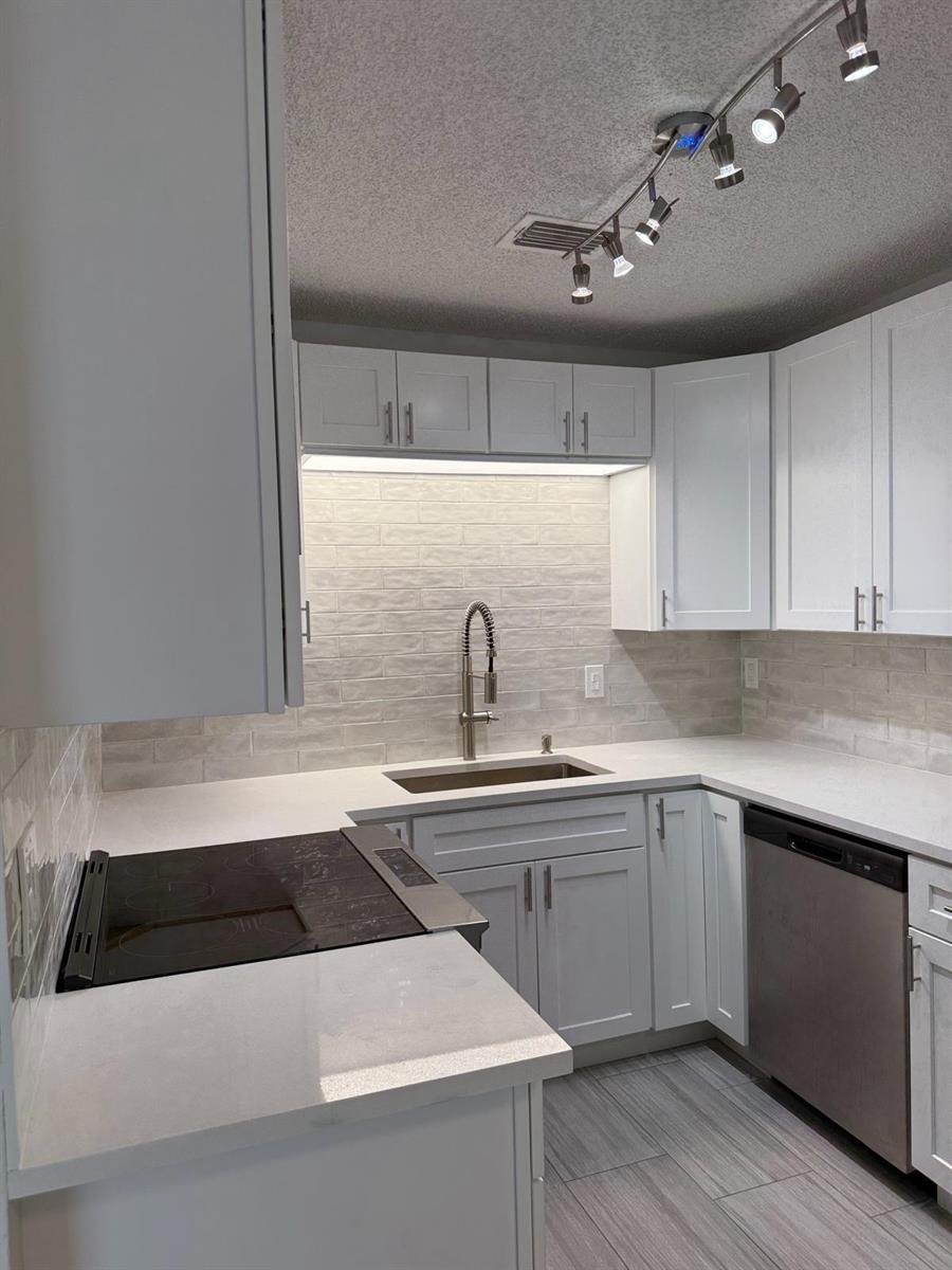 A modern kitchen features white shaker cabinets, quartz countertops, a subway tile backsplash, and stainless appliances — 2630 W 28th Street, Riviera Beach FL 33404, RIVIERA BEACH, FL