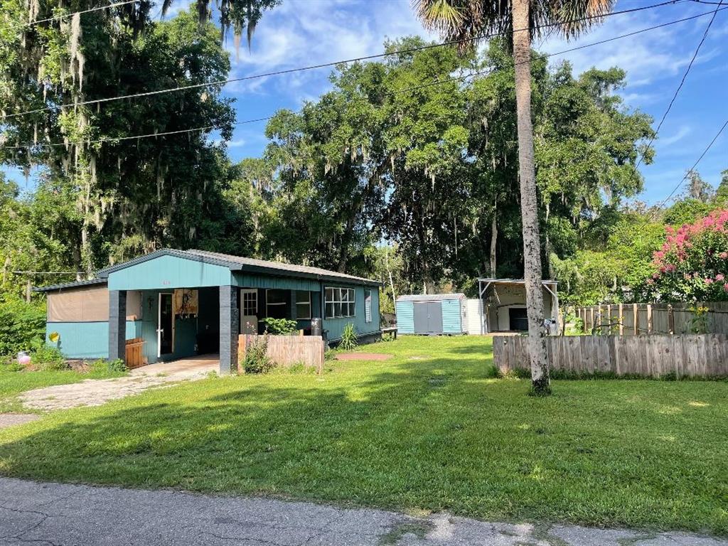 A teal single-story house with a covered porch sits on a grassy lot with trees — 430 SE 74TH STREET, GAINESVILLE, FL